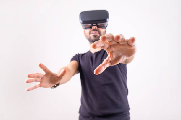 Young man using VR glasses headset gesturing excited, portrait on light background. Virtual reality, future technology, education video gaming.