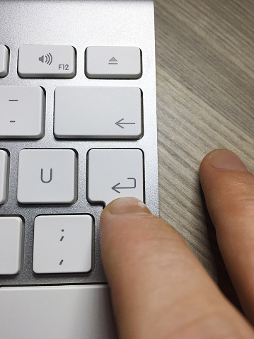 Using computer. Finger pushing computer enter key