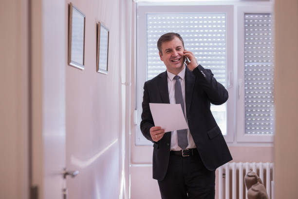 istock Cheerful businessman holding document when having a phone conversation with coworker 1386948141
