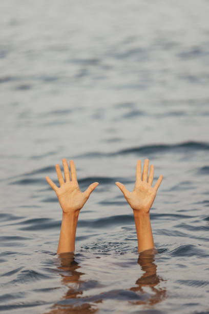 istock Unrecognizable woman hands waving for help, drowning into the sea 1386949361