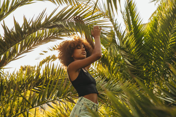 istock Pretty young afro woman among palm trees 1386949632