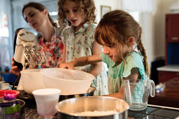 istock Mother and young daughters baking a cake at home. 1386949928
