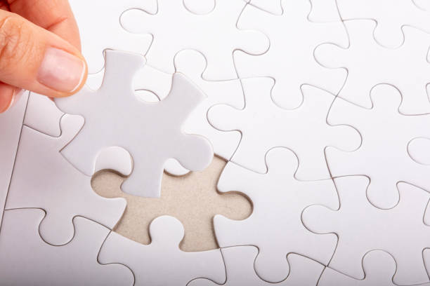 istock Placing last jigsaw puzzle piece on blank game board 1386950700