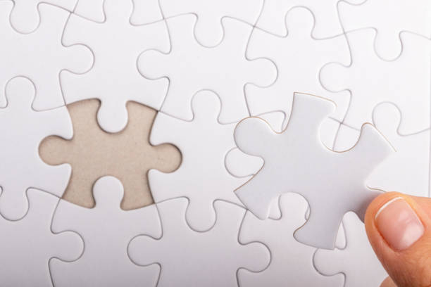 istock Comparing last missing jigsaw piece with blank space of puzzle board 1386950702