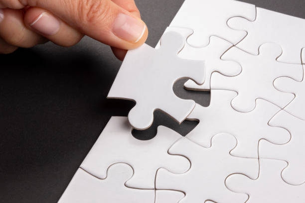 istock Fingers matching last missing jigsaw puzzle piece. 1386950898