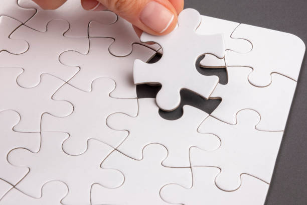 istock Fingers placing last missing jigsaw puzzle piece. 1386950946