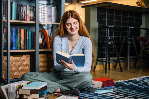 istock Young female student siting on the floor and reading a book 1386952024
