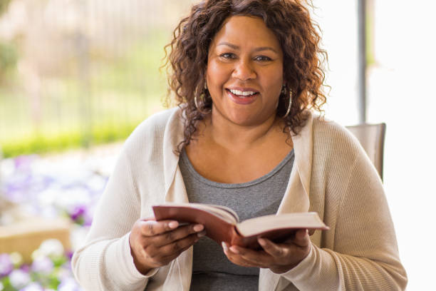 Mature African American woman sitting outside reading. stock photo
