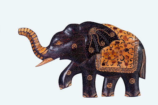 The wall decoration is made of wood, shaped like an elephant, and is painted with batik motif, isolated on white background.