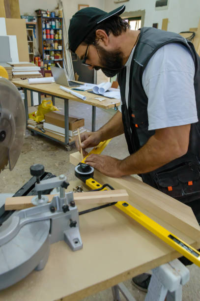 istock Carpenter is Using a Protractor to Measure a Wooden Plank at Workshop. 1386962177