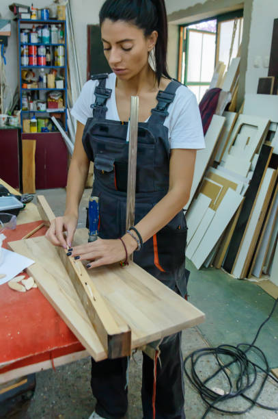 istock Female Carpentry Worker is Preparing a Wooden Plank for Woodwork. 1386962306