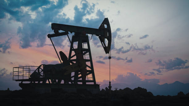 Working Pumpjack On Sunset Pump jack silhouette against a sunset sky. north sea oil and gas stock pictures, royalty-free photos & images