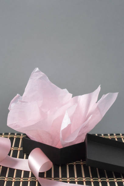 istock Unwrapped gift box with pink paper and satin ribbon 1386966556