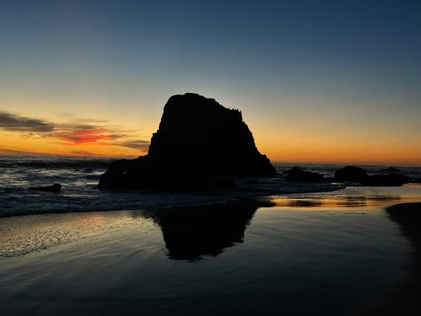 rock at sunset beach riflessione - reflection water rock beach foto e immagini stock