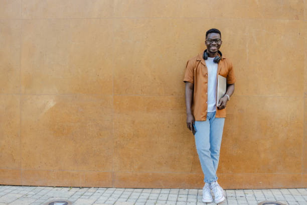 istock Man with laptop posing against orange background 1386971902