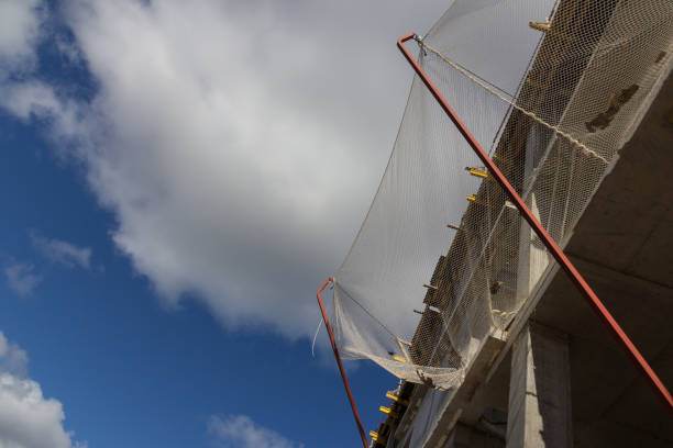 rete di sicurezza per la costruzione. una rete di costruzione che impedisce agli oggetti di cadere da un edificio in costruzione. la rete di costruzione è installata ai piani superiori dell'edificio - rete di sicurezza foto e immagini stock