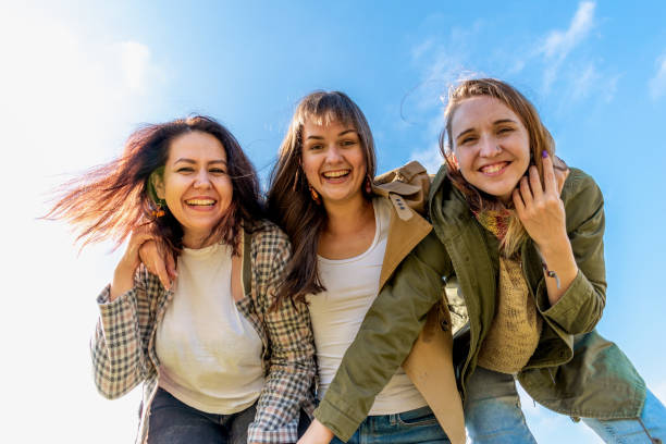 Group of women raising up a friend with a telephone to the sky. Modern communications, cloud computing concept.