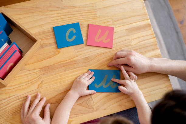 Montessori material. Mom helps her daughter learn letters using the rough alphabet. Montessori material. Mom helps her daughter learn letters using the rough alphabet. Child toddler girl. Concept of learning. Development of motor skills. montessori stock pictures, royalty-free photos & images