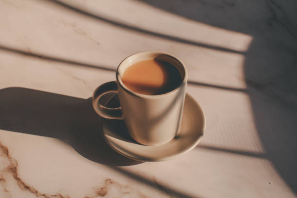 istock Hot coffee in ceramic cup on marble table under morning sunlight from window. Dreamy and relaxed mood. 1386976203