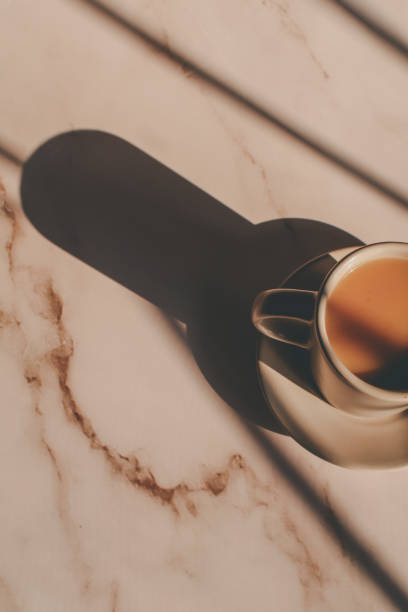 istock Hot coffee in ceramic cup on marble table under morning sunlight from window. Dreamy and relaxed mood. 1386976204