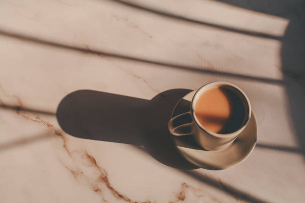 istock Hot coffee in ceramic cup on marble table under morning sunlight from window. Dreamy and relaxed mood. 1386976205