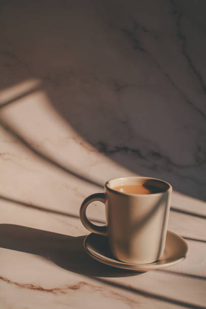 istock Hot coffee in ceramic cup on marble table under morning sunlight from window. Dreamy and relaxed mood. 1386976206