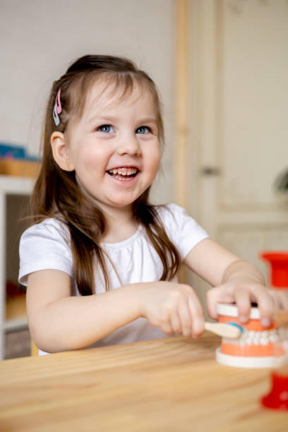 istock Montessori material. Mom teaches her daughter how to brush her teeth while playing. 1386976356