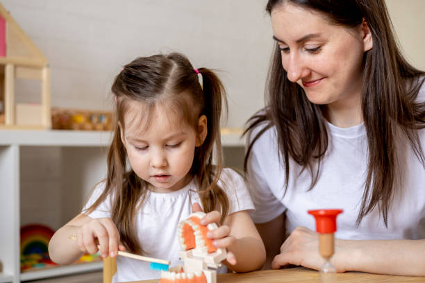 istock Montessori material. Mom teaches her daughter how to brush her teeth while playing. 1386977189