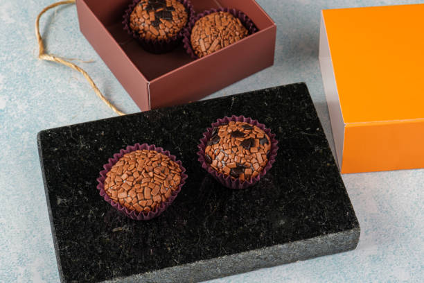 traditional and bitter brigadeiros on a black marble stone, next to an open box. - craft chocolate candy black box imagens e fotografias de stock