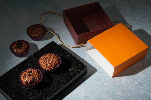 low key photo. brigadeiros arranged on a shiny black marble stone, next to a box with sisal rope_side view. - craft chocolate candy black box imagens e fotografias de stock