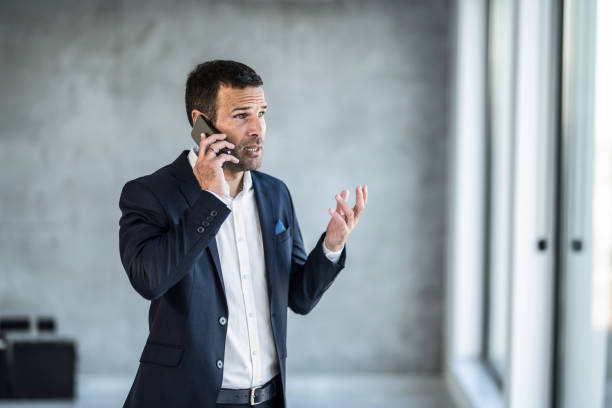 Frustrated businessman talking on phone in the office. stock photo