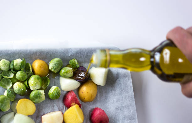 vierte a mano aceite de oliva en la bandeja de verduras cena - brussels sprout raw brown close up fotografías e imágenes de stock