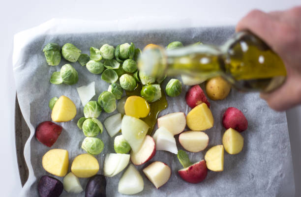 vierte a mano aceite de oliva en la bandeja de verduras cena - brussels sprout raw brown close up fotografías e imágenes de stock