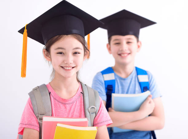 Happy boy and  girl in graduation cap holding books stock photo