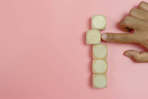 istock hand finger pointing empty wooden cube block on pink background. create education shape symbol simple. 1386996081