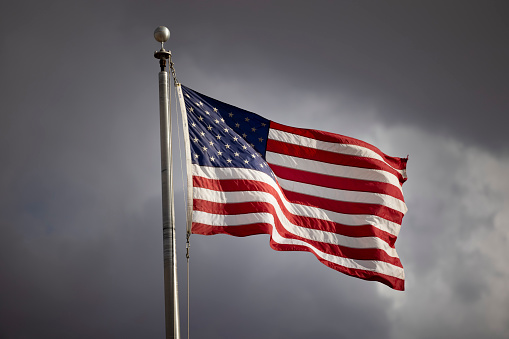 An American flag waving in the wind on a cloudy day.