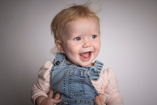 A 1 year old baby girl on a studio background
