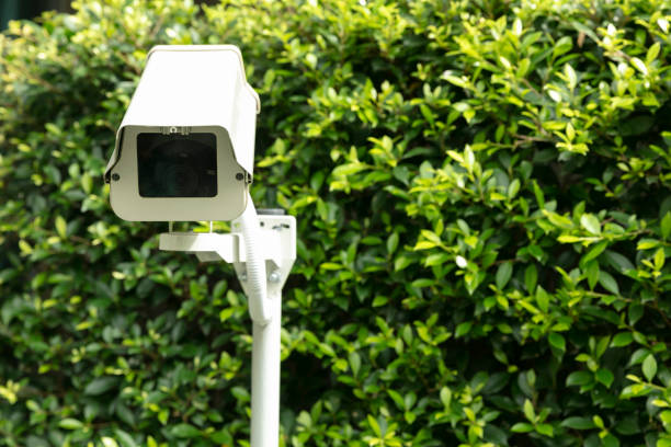 istock Surveillance camera on pole infant of tree leaves background 1387006150