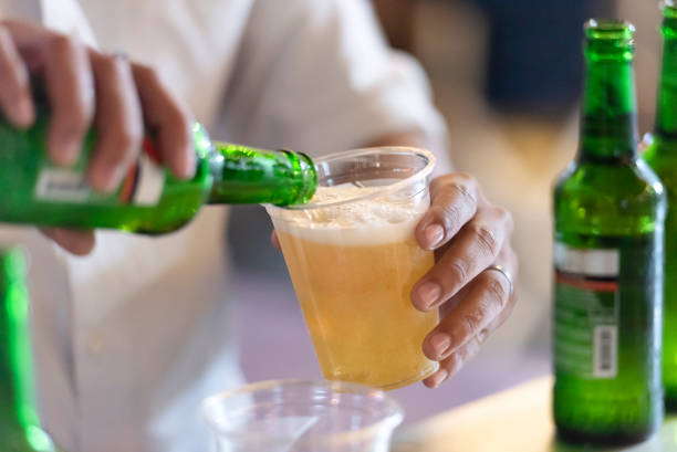 istock Hand pouring beer into plastic glass 1387006171