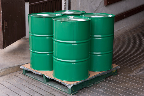 Group of green color metal barrels on pallet waiting for transfer