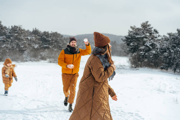 Young man and woman playing snowball on mountains background in winter season