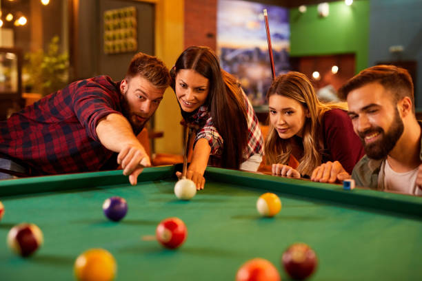 istock Group of friends having fun while playing pool in a local pool hall 1387013874