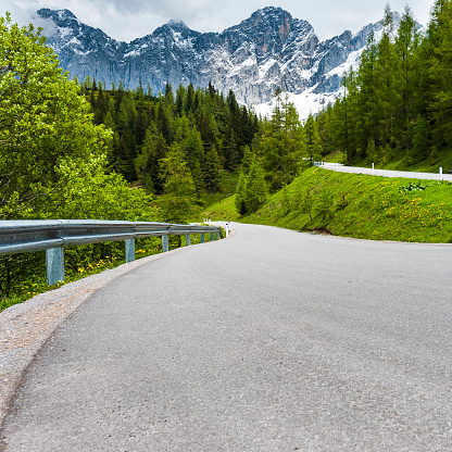 Winding asphalt road in Austrian landscape with forests, fields, pastures and meadows