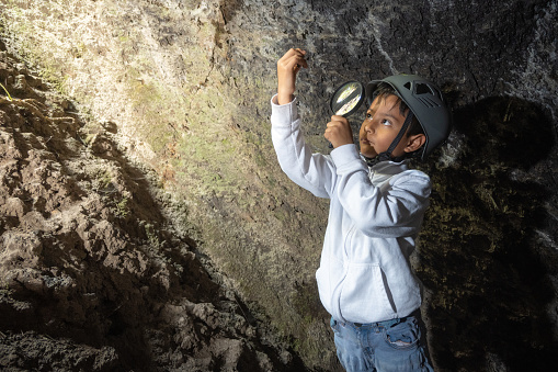 Boy exploring and observing rocks inside a cave
