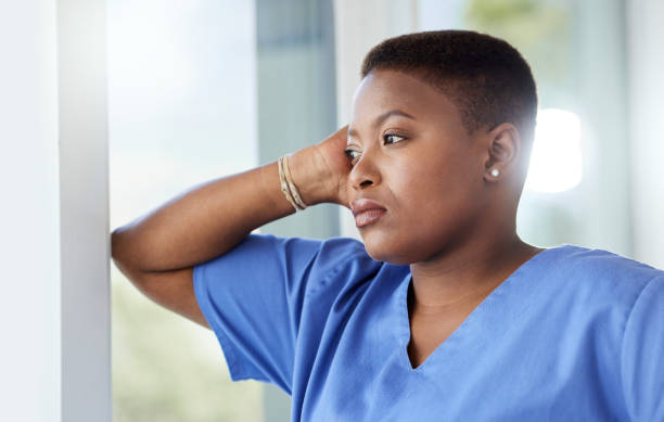 foto de una enfermera que parece estresada mientras está de pie en un hospital - doctor tired protective workwear sadness fotografías e imágenes de stock