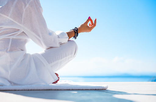 Woman meditating outdoors on terrace with beautiful sea view
