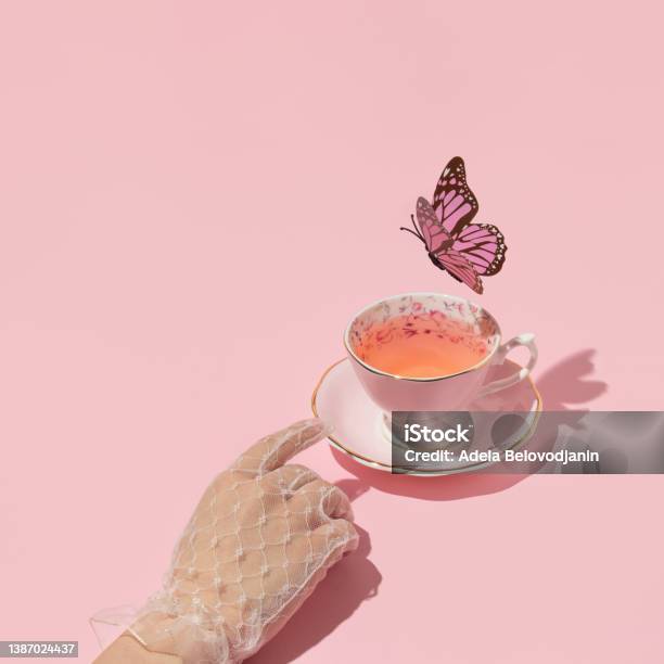 Woman Hand Reaching Vintage Cup Of Tea And Butterfly Flying Above On Pastel Pink Background 80s 90s Retro Aesthetic Spring Or Summer Concept Minimal Fashion Romantic Idea Stock Photo - Download Image Now