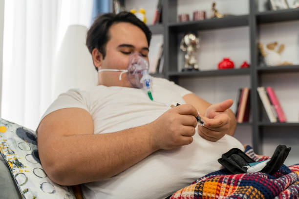 young man sits in a sofa with an oxygen mask and  measuring blood sugar level stock photo