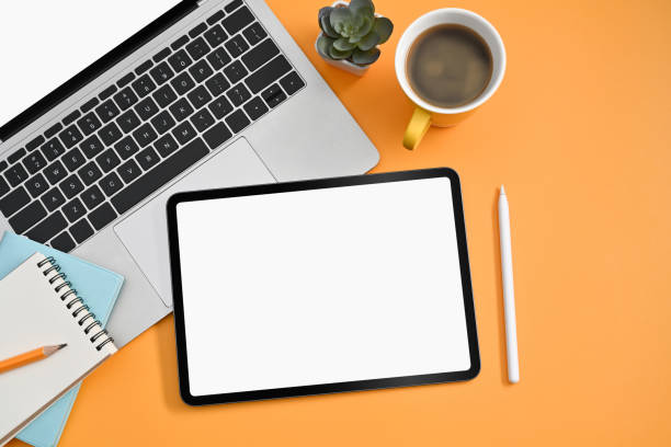 istock Top view digital tablet, stylus pen, laptop, coffee cup and notebook on yellow background. 1387024747