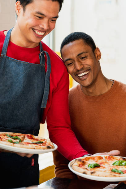 istock Vertical portrait African man smiling while looking at pizza served by his friend. 1387024912